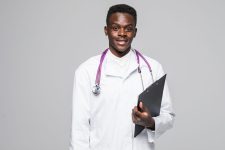 Friendly Afro-American doctor holding a clipboard and smiling at the camera